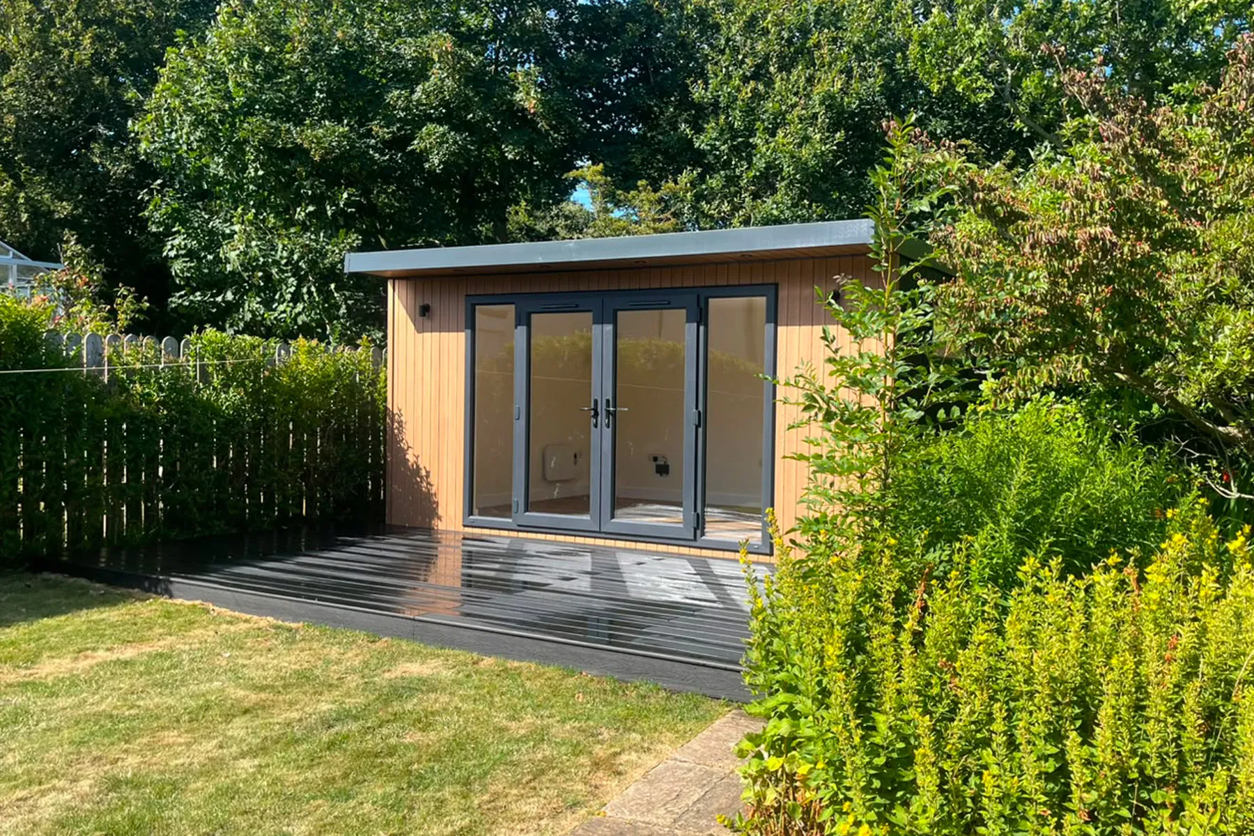 A dark-clad Pent Haus garden room in a landscaped garden